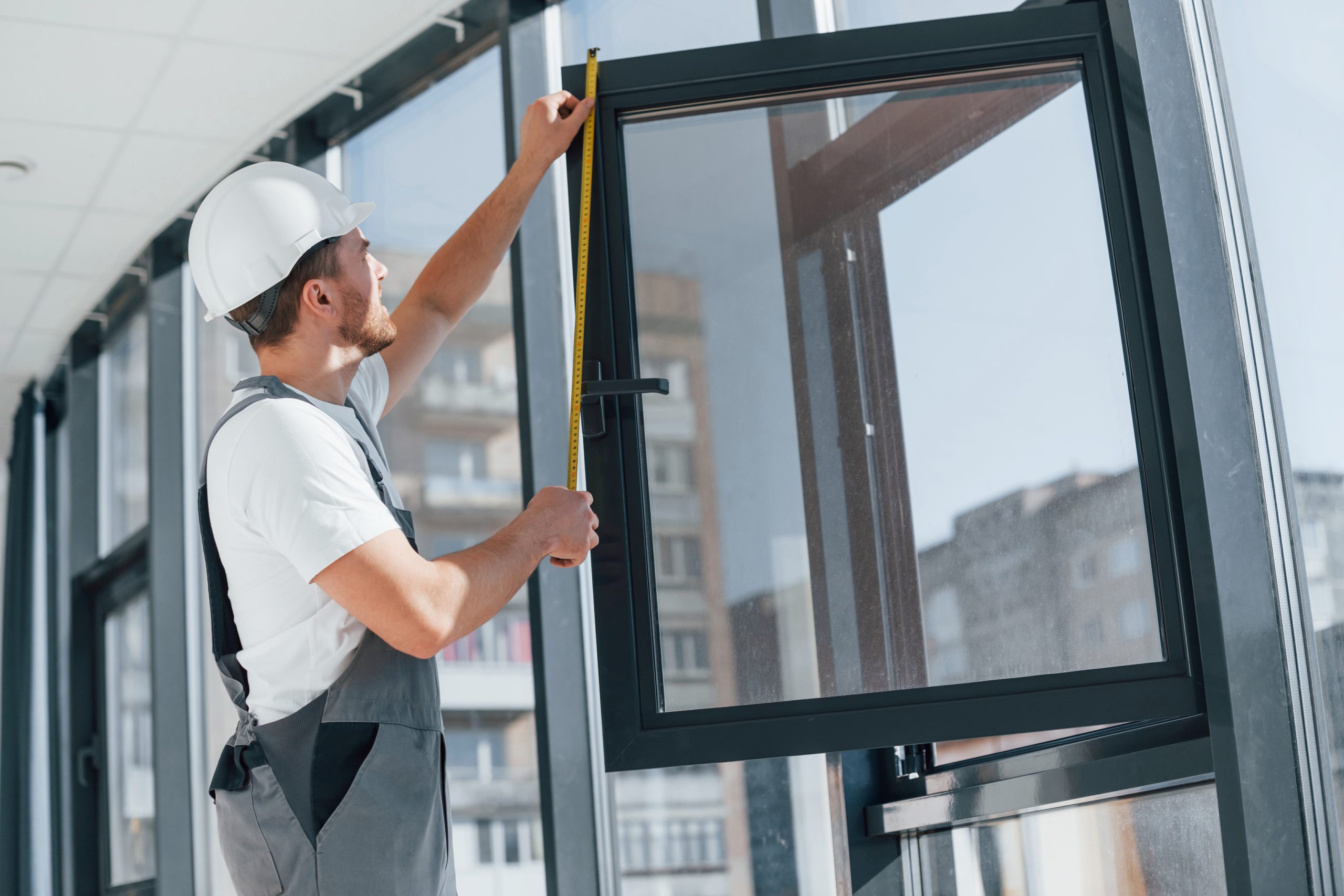 Repairman measuring window indoors.