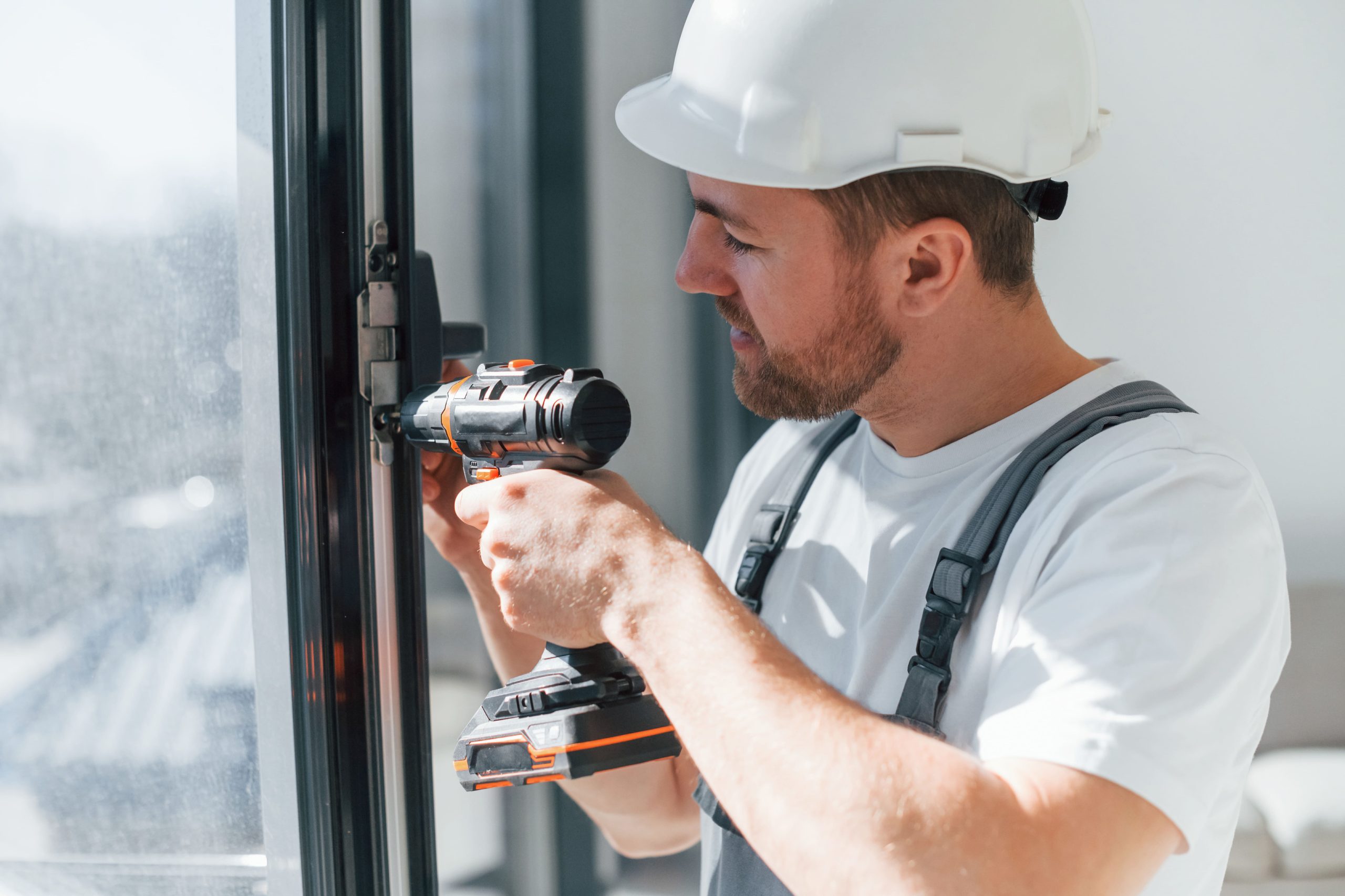 Repairman installing window with drill.